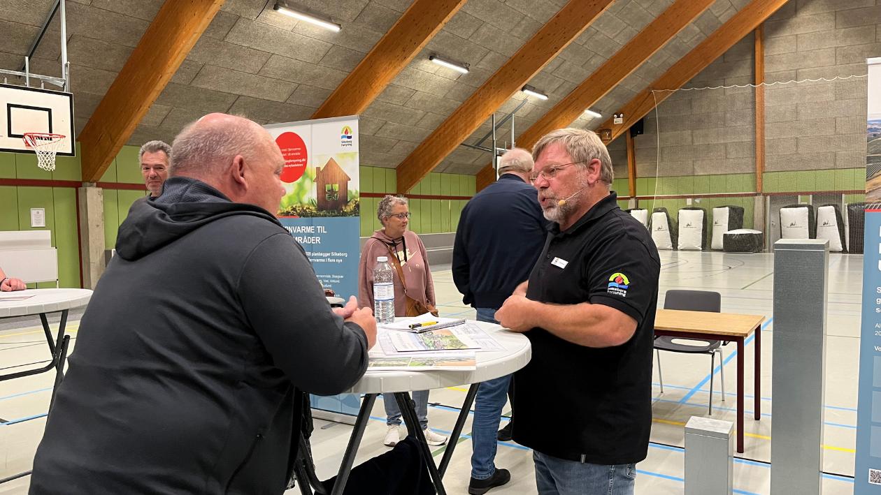 Borger og medarbejder hos Silkeborg Forsyning snakker sammen ved cafebord